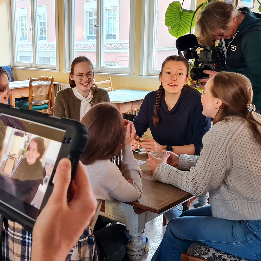 Kameramann dreht Lerngruppe von Informatikstudenten in einem Café